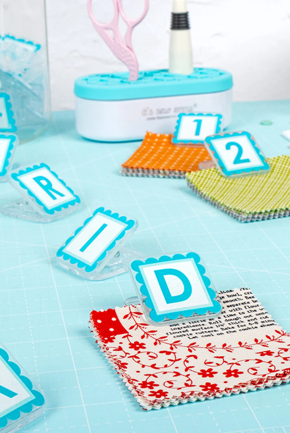 Quilt Clips with letter tiles and fabric on a blue surface