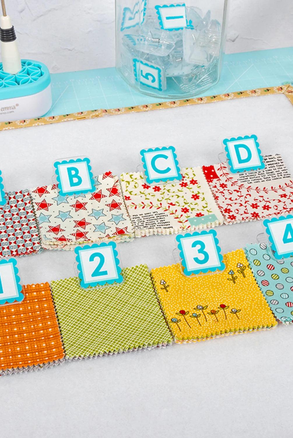Colorful fabric swatches with letters and numbers on a white surface. Quilt Clips with letter tiles and fabric on a blue surface