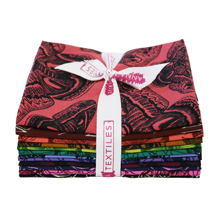 Stack of colorful fabric bundles tied with a white ribbon on a white Anna Matia Textiles Fabric