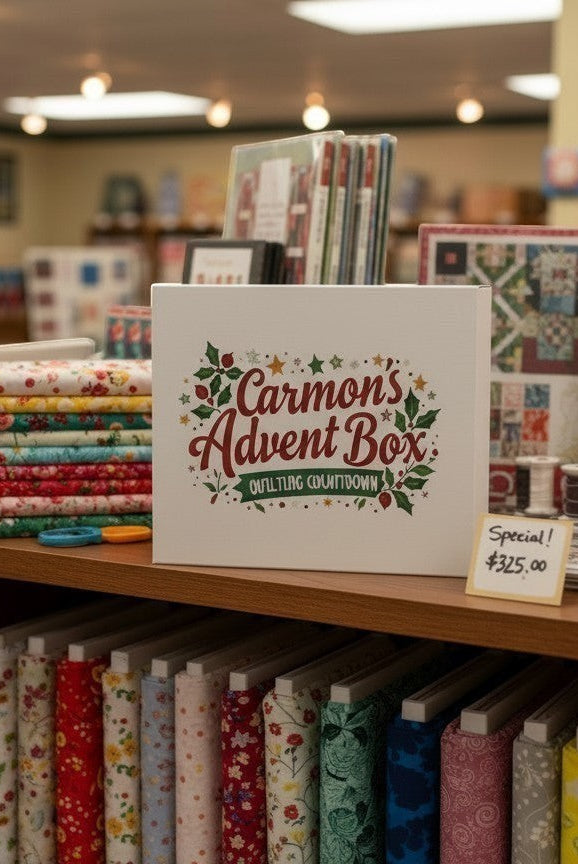 Carmon's Quilt Shop limited-edition advent box displayed on a wooden shelf with stacks of colorful quilting fabrics.