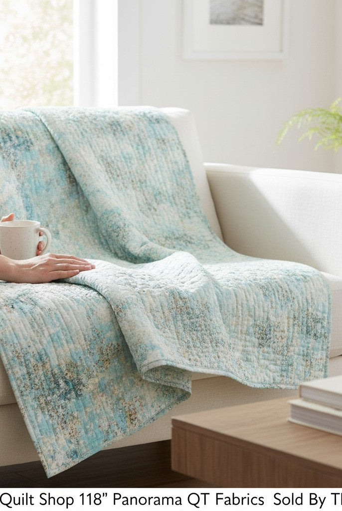 Carmon's Quilt Shop light aqua mottled texture 118 inch wide cotton quilting fabric draped over a white sofa