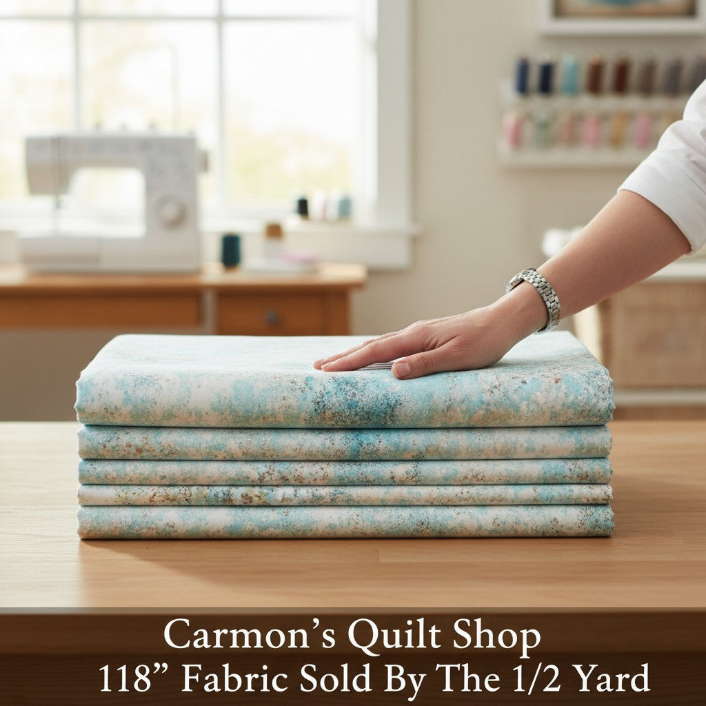 Carmon's Quilt Shop light aqua mottled texture 118 inch wide cotton quilting fabric folded on a wooden table
