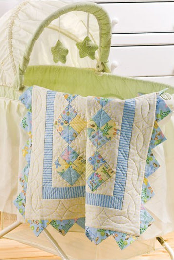 Carmon's Quilt Shop baby quilt featuring pastel blue and yellow patchwork patterns draped over a bassinet