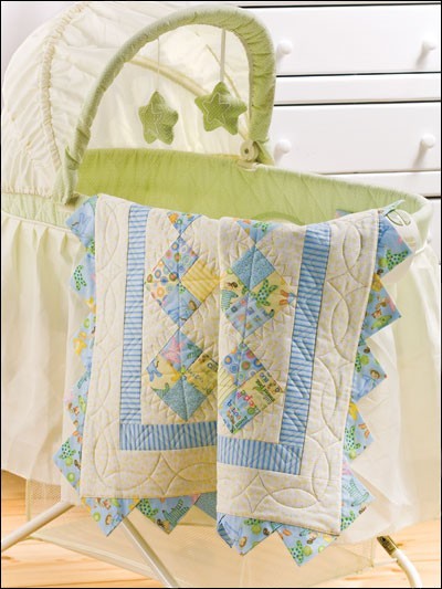Carmon's Quilt Shop baby quilt featuring pastel blue and yellow patchwork patterns draped over a bassinet