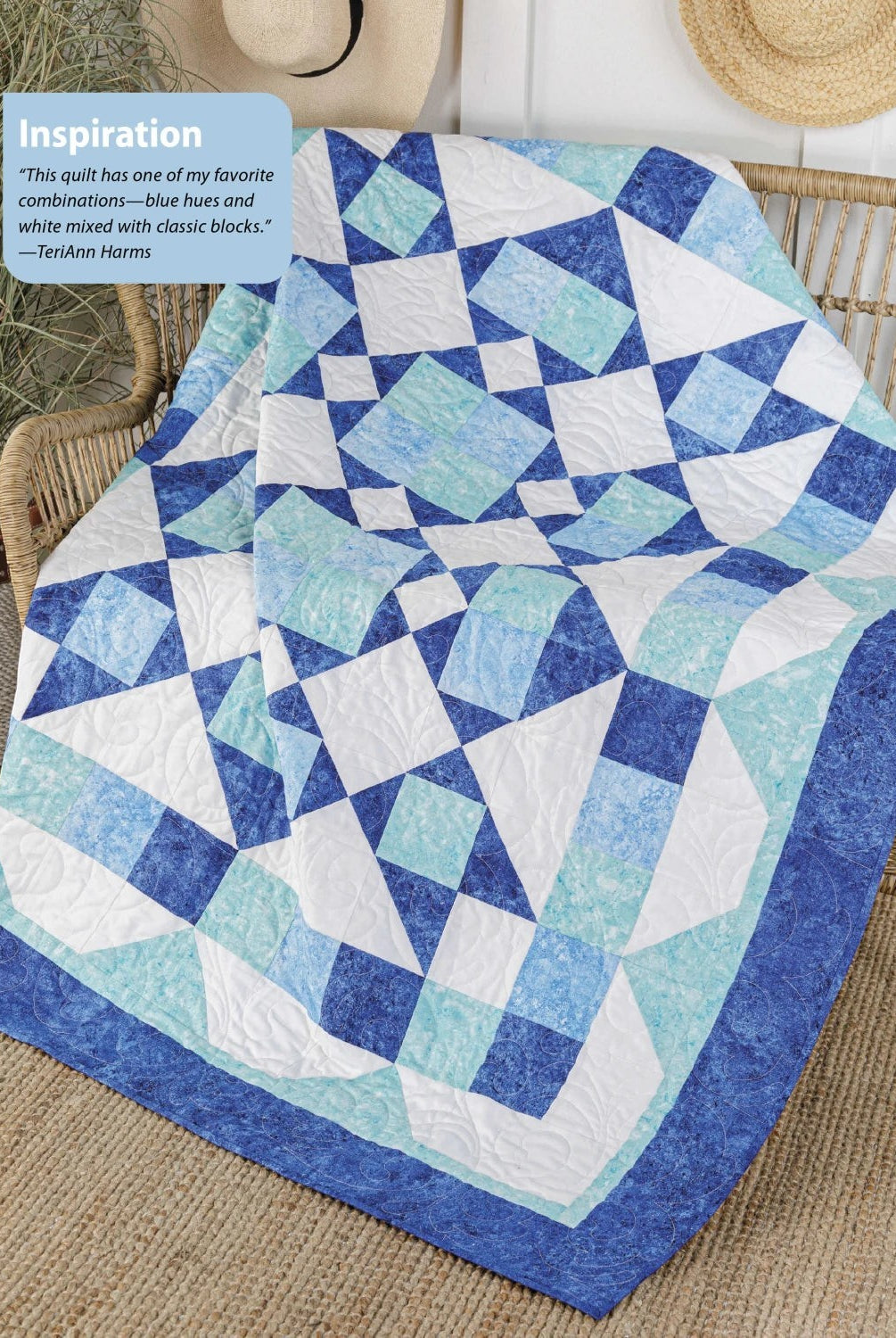 Carmon's Quilt Shop blue and white geometric quilt pattern draped over a wicker chair with a straw hat