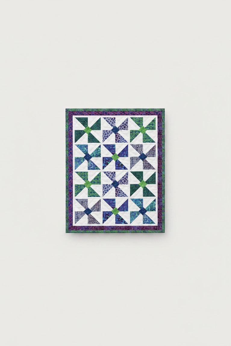 Carmon's Quilt Shop Fabric Café Bold in Bloom lap quilt with blue and green pinwheel blocks on a white background.