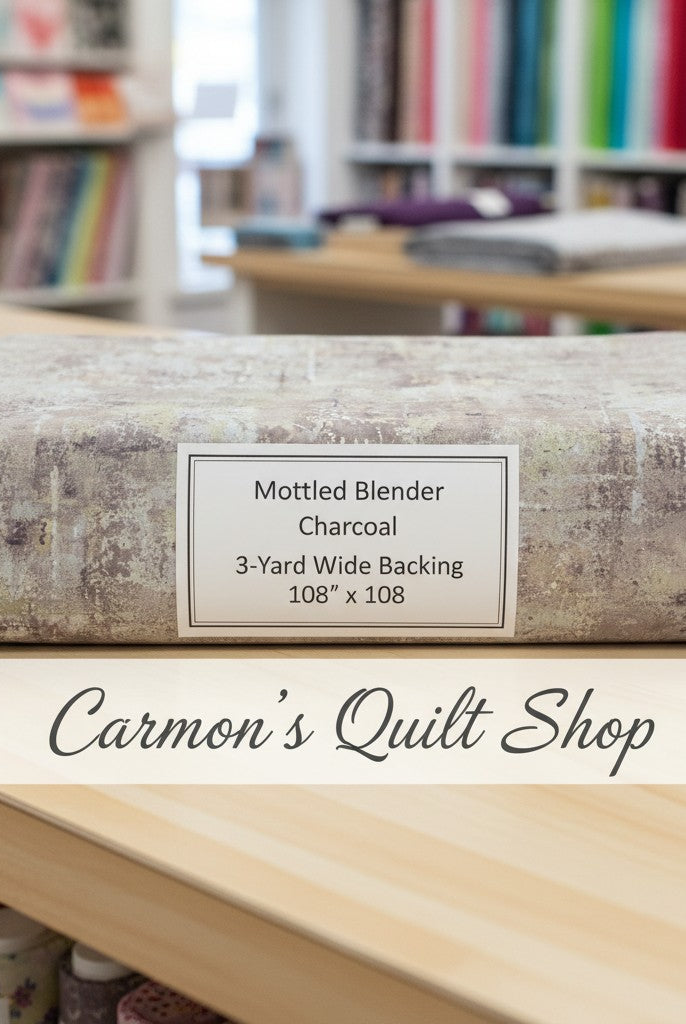 Carmon's Quilt Shop charcoal mottled blender 108-inch wide cotton quilt backing fabric folded on a wooden table.