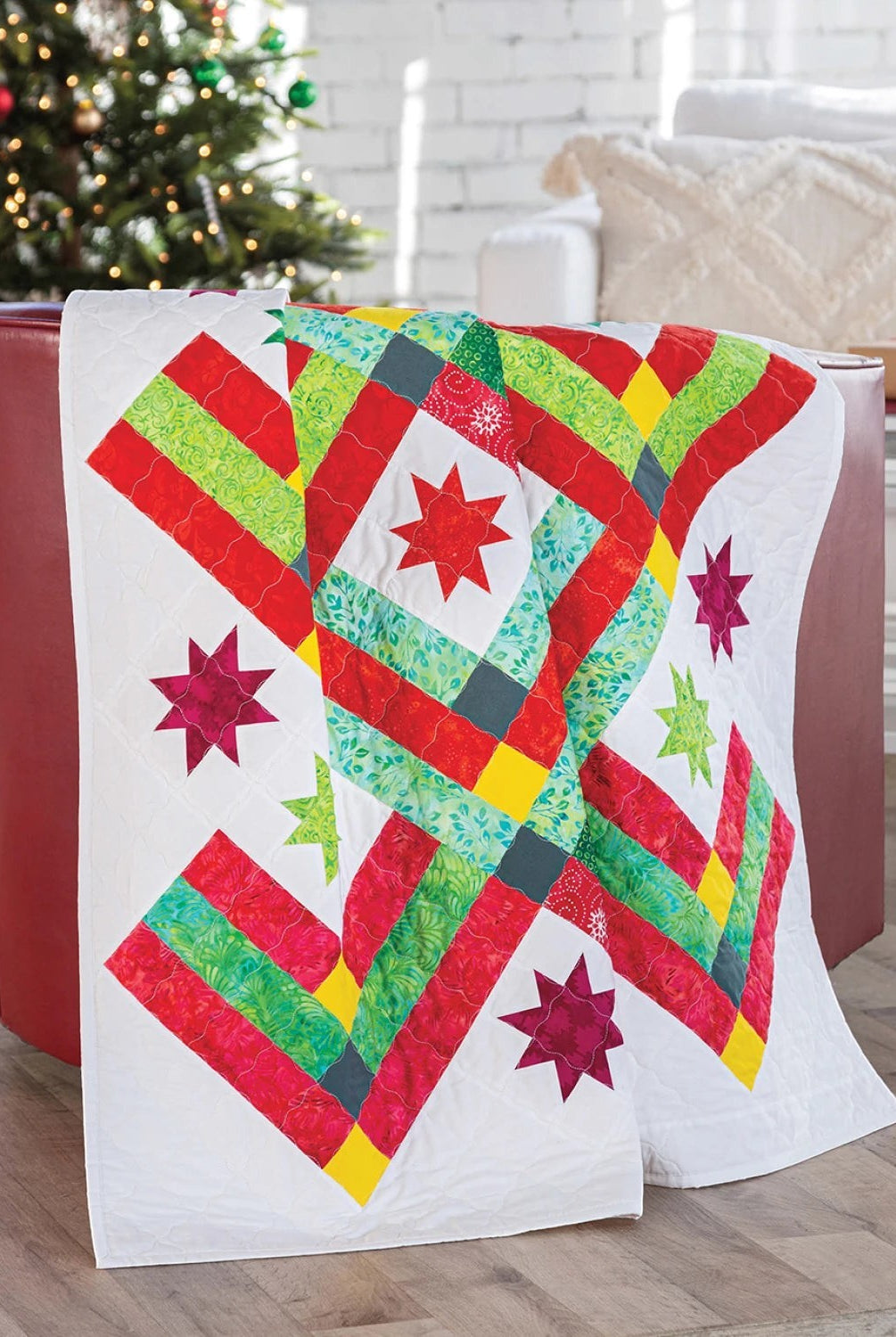 Carmon's Quilt Shop Christmas quilt featuring red, green, and yellow star patterns on a white background
