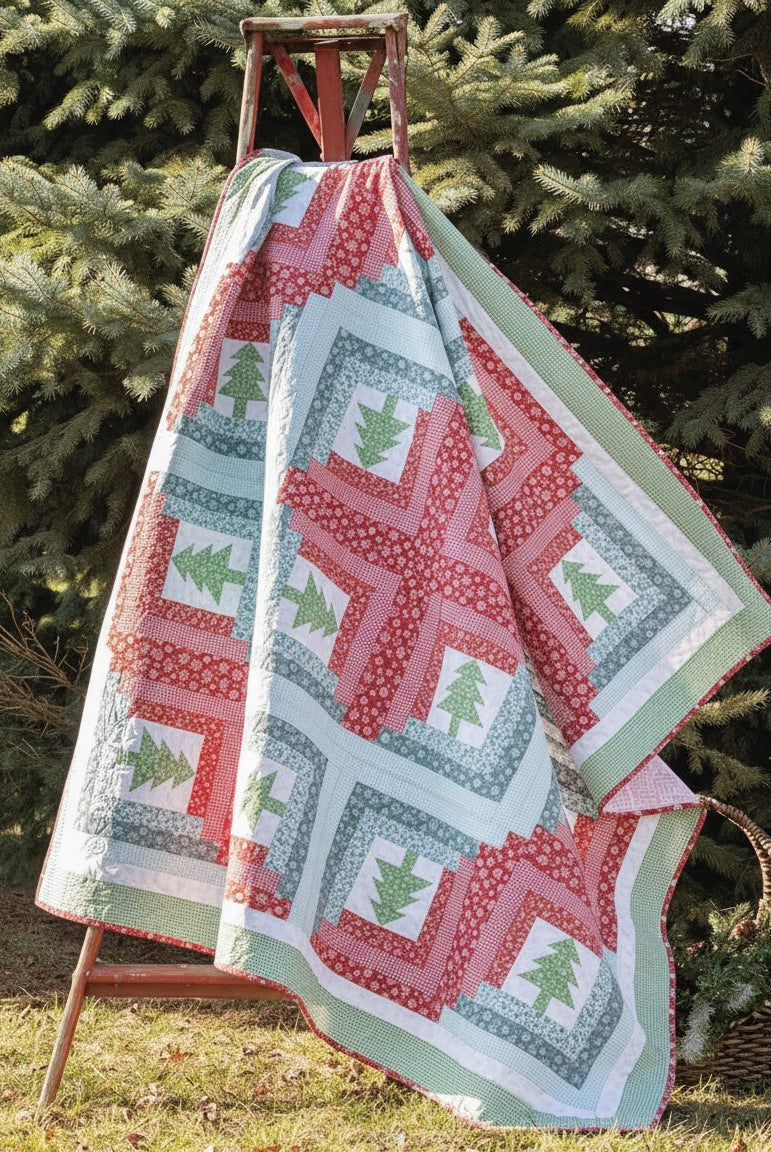 Carmon's Quilt Shop Christmas quilt featuring red and green tree patterns draped over a wooden ladder outdoors.