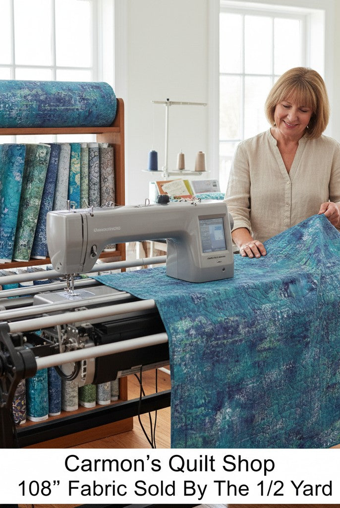 Carmon's Quilt Shop denim blue mottled 108-inch wide cotton quilting fabric on a longarm machine in a sewing studio.