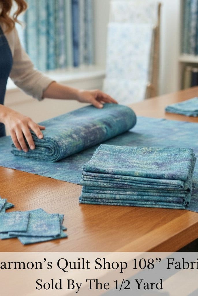 Carmon's Quilt Shop QT Fabrics mottled denim blue 108 inch wide quilting cotton fabric folded on a wooden table.