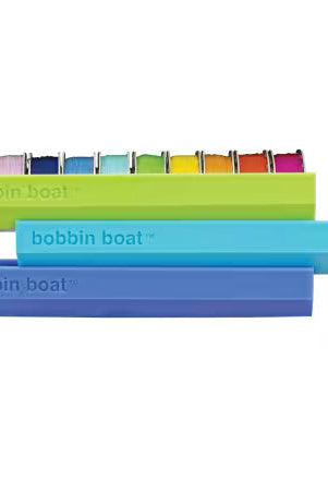 Carmon's Quilt Shop Dritz Bobbin Boat organizers in green, blue, and purple for sewing and quilting storage.