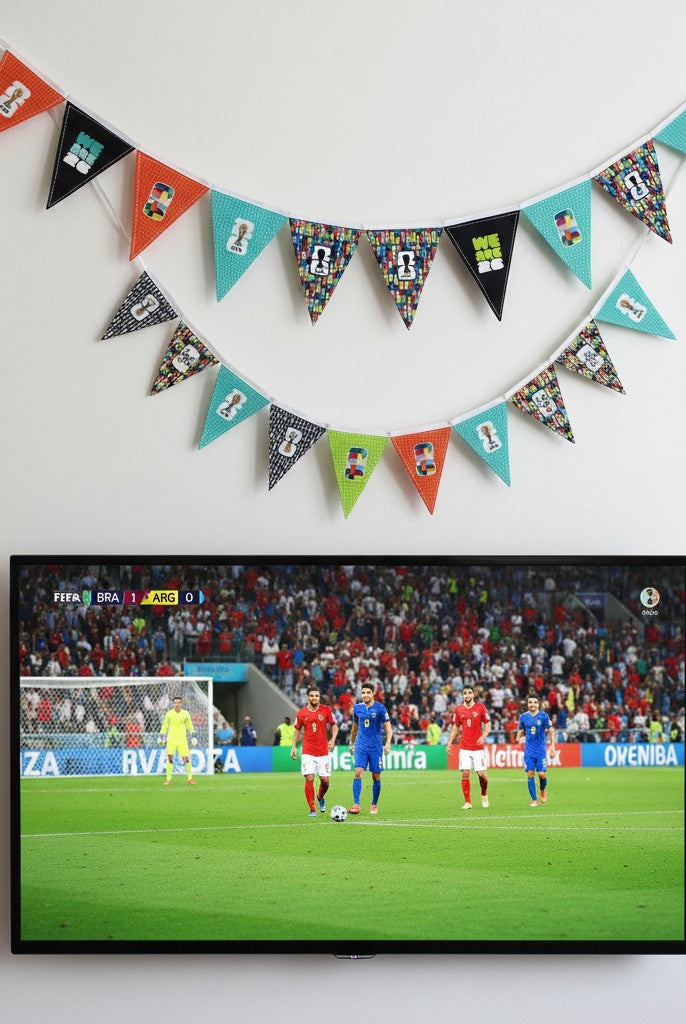 Carmon's Quilt Shop FIFA World Cup fabric panel with geometric pennants in orange, teal, black, and green with football motifs.