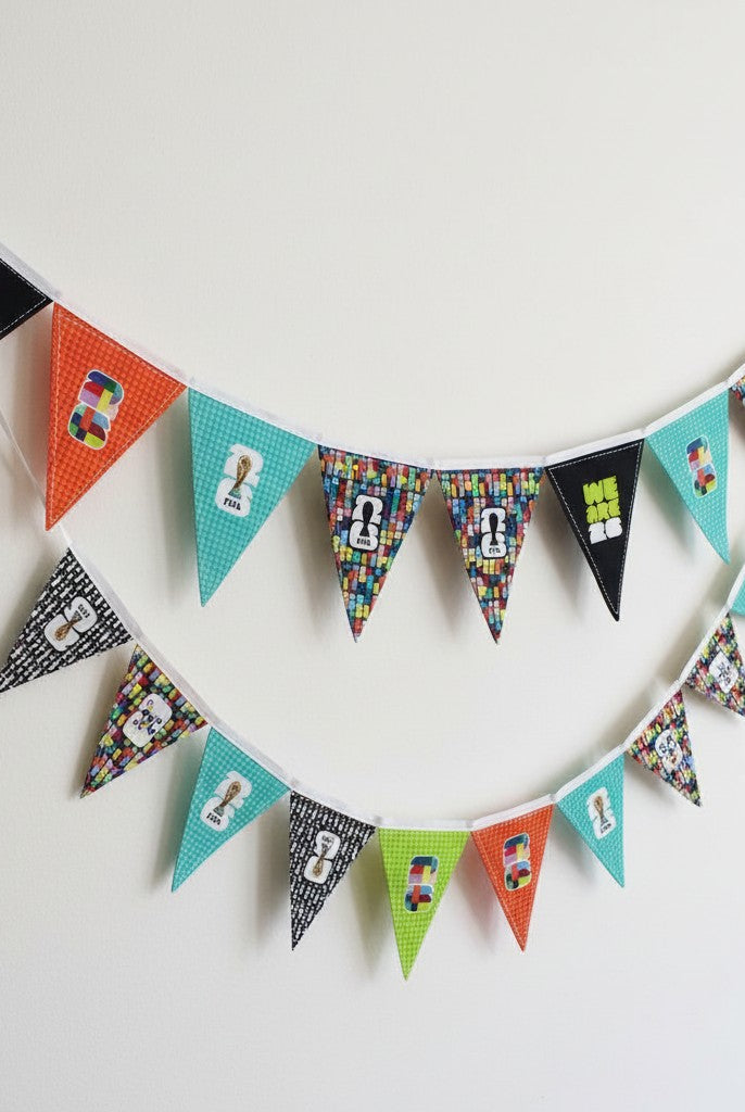 Carmon's Quilt Shop FIFA World Cup fabric panel with geometric pennants in teal, orange, black, and green with logos and text.