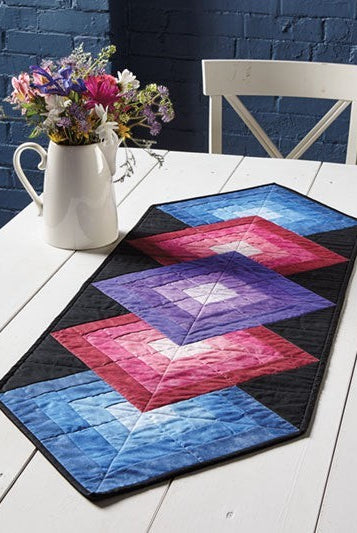 Carmon's Quilt Shop Log Cabin Variations quilt pattern book featuring a colorful geometric table runner project