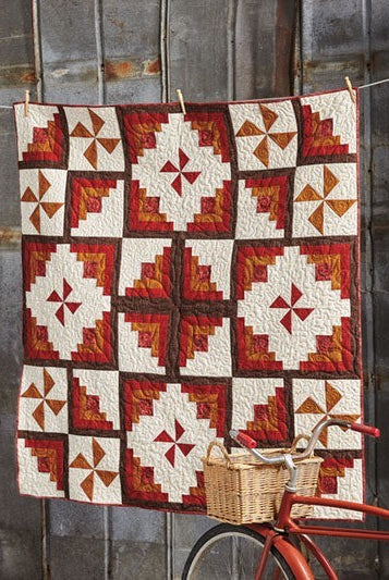 Carmon's Quilt Shop Log Cabin Variations quilt featuring red, orange, and cream geometric fabric patterns.