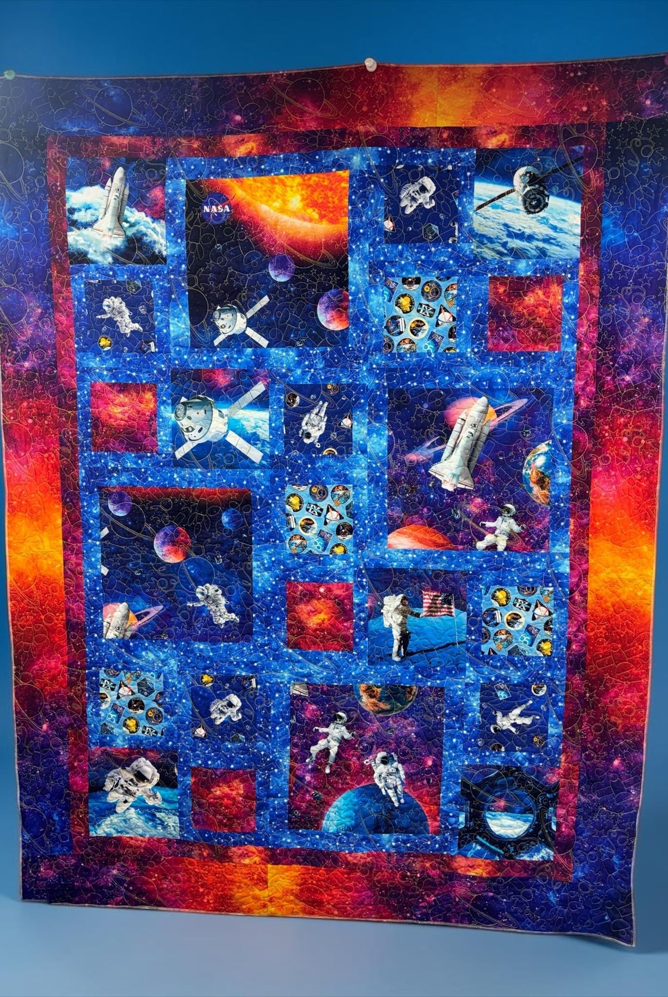 Carmon's Quilt Shop Space Odyssey Hopscotch NASA quilt featuring vibrant space imagery, astronauts, and rockets.