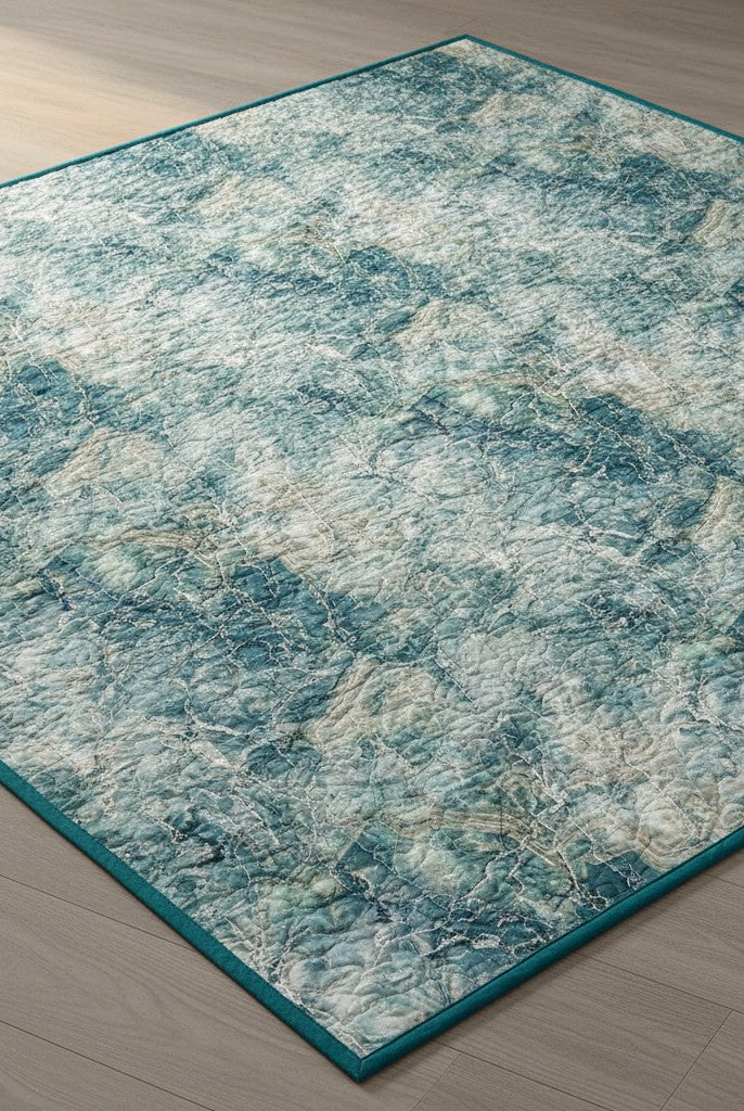 Carmon's Quilt Shop Northcott Smooth Sailing marble pattern quilt fabric in teal, blue, and white on a wood floor.