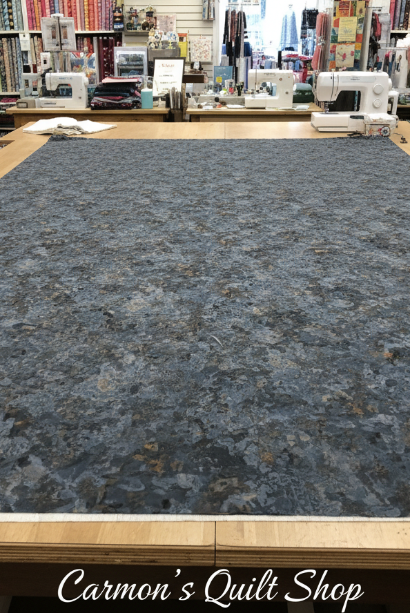 Carmon's Quilt Shop Chroma Obsidian black textured 108-inch wide cotton quilt backing fabric on a cutting table.