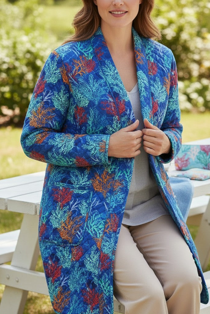 Carmon's Quilt Shop quilted jacket in Oceana Coral fabric featuring vibrant orange and blue reef patterns outdoors.