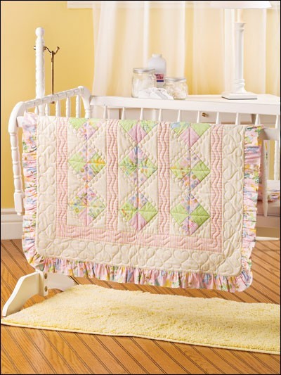 Carmon's Quilt Shop baby quilt featuring pastel patchwork squares, ruffled edges, and heart-patterned quilting.