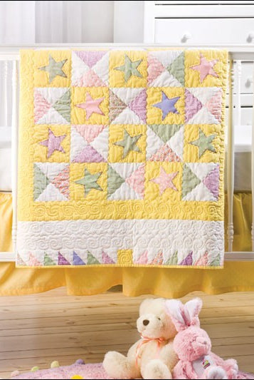 Carmon's Quilt Shop baby quilt featuring a pastel star pattern with yellow, pink, and green fabric on a crib.