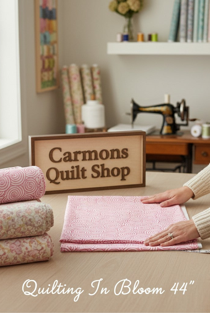 Carmon's Quilt Shop pink daisy scroll blender cotton fabric from the Quilting in Bloom collection on a work table.