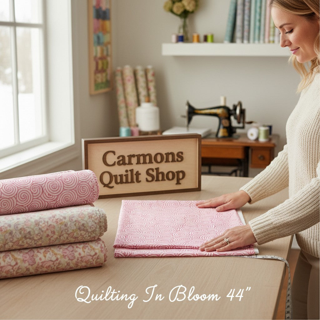 Carmon's Quilt Shop pink daisy scroll blender cotton fabric from the Quilting in Bloom collection on a work table.