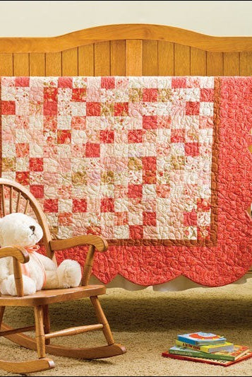 Carmon's Quilt Shop keepsake baby quilt pattern book featuring a pink and cream patchwork quilt with scalloped edges