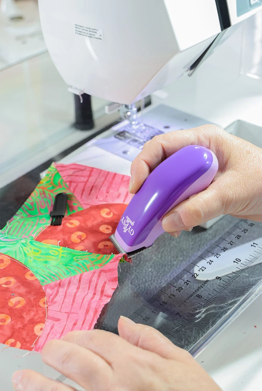 Carmon's Quilt Shop purple Gypsy Snip-N-Pin battery-operated thread shaver removing stitches from colorful quilt fabric
