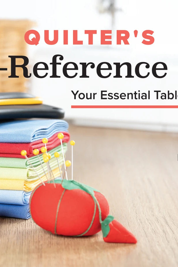 Carmon's Quilt Shop Quilter's Quick-Reference Guide tabletop book with sewing tools, fabric, and pin cushion.