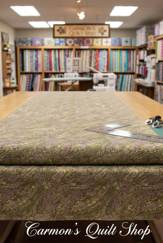 Carmon's Quilt Shop Meadow Breeze sage green floral 108-inch wide cotton quilt backing fabric on a cutting table.