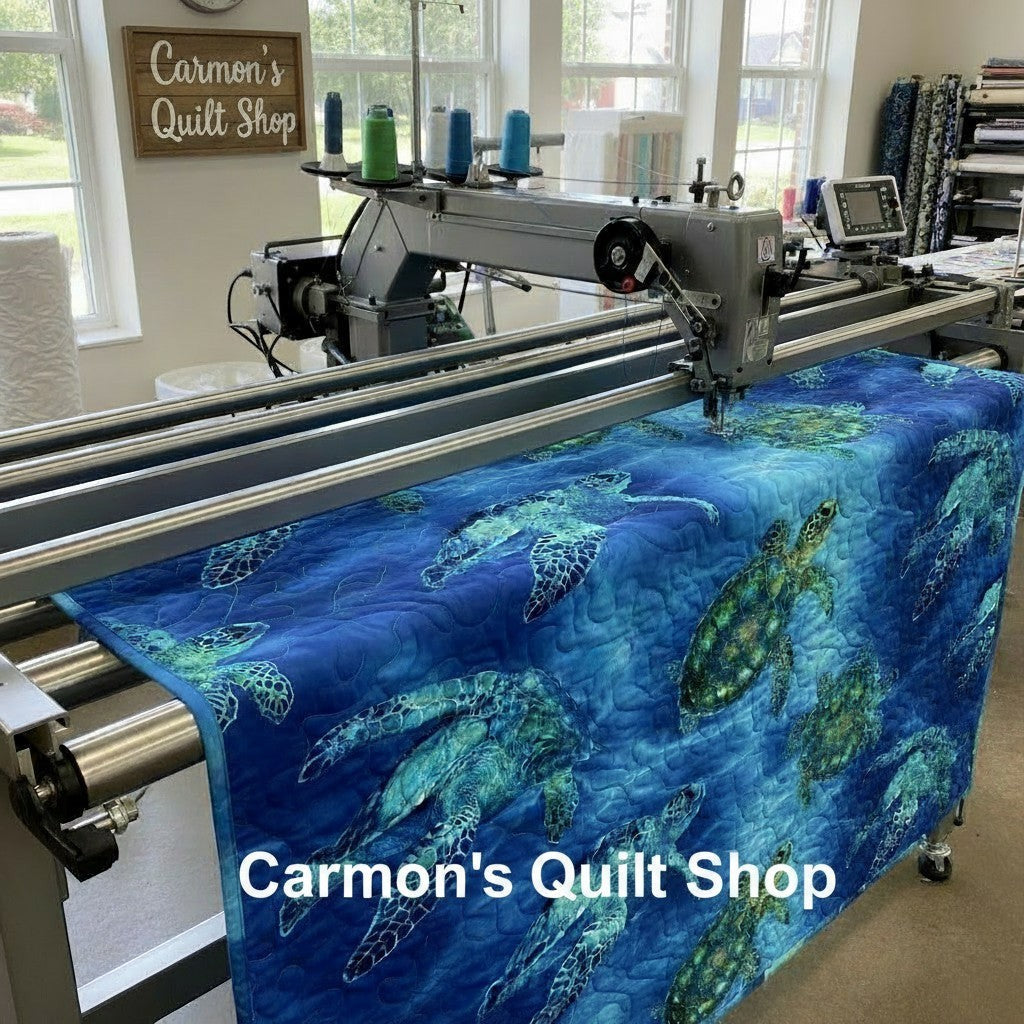 Carmon's Quilt Shop sea turtle patterned 108-inch cotton quilting fabric being machine quilted on a longarm frame.