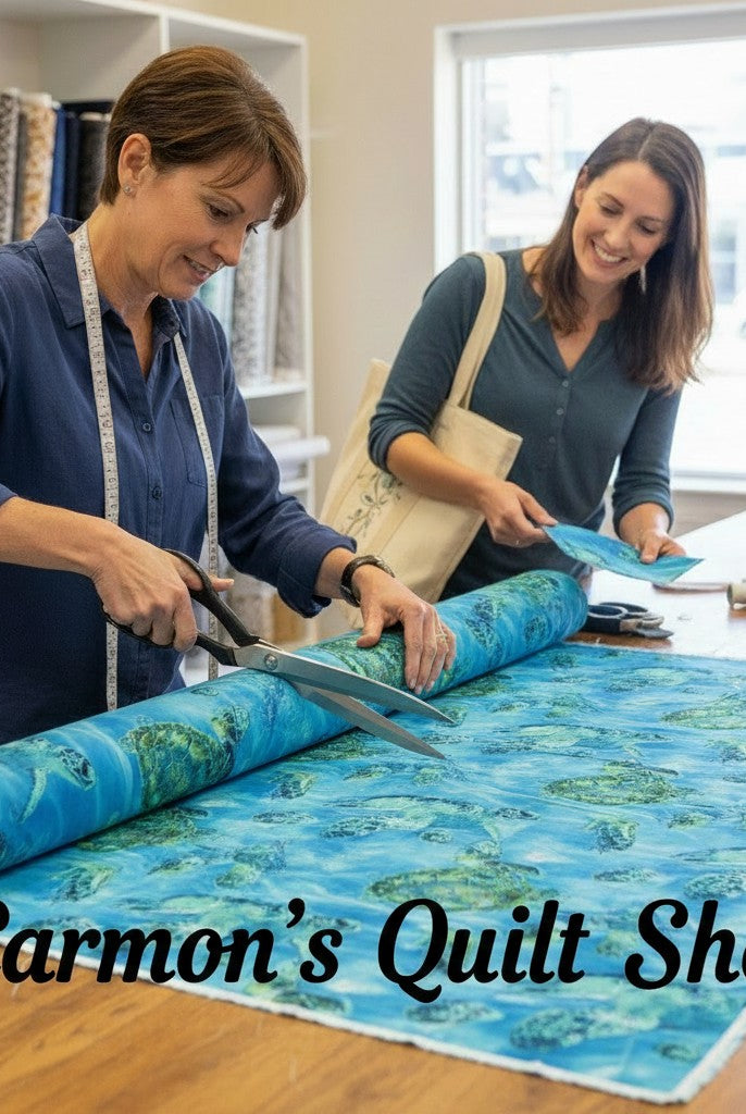 Carmon's Quilt Shop staff cutting blue sea turtle patterned 108-inch cotton quilting fabric on a wooden table.