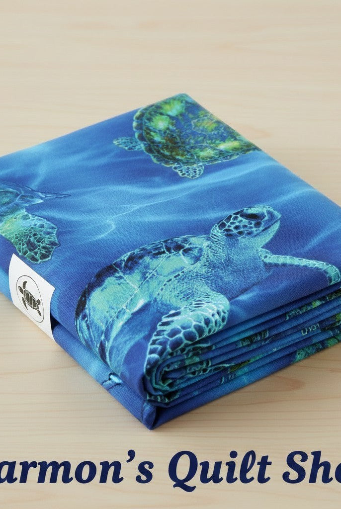Carmon's Quilt Shop 108-inch wide cotton quilting fabric featuring a vibrant blue sea turtle underwater print.