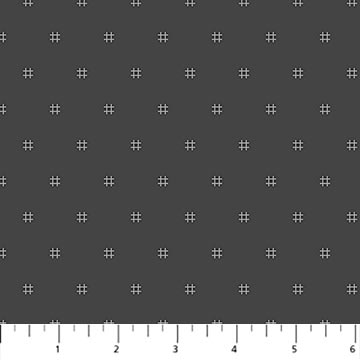 Fabric with a pattern of small white crosses on a dark gray background, with a ruler at the bottom.