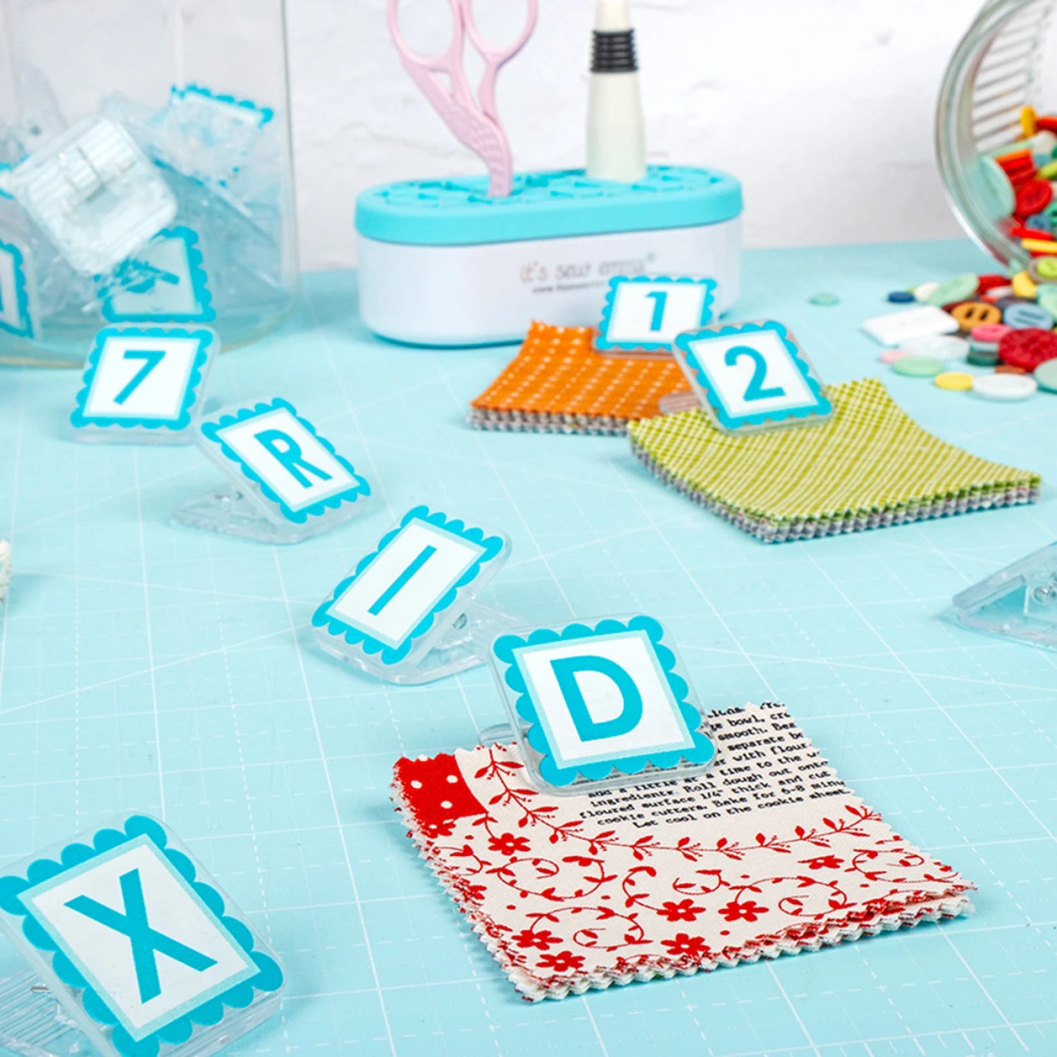 Quilt Clips with letter tiles and fabric on a blue surface