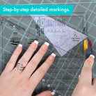 Hands using a ruler and cutting tool on a cutting mat with text 'Step-by-step detailed markings.' Creative Grids Quilt Ruler Kitty Cornered # CGRDH5 - Carmon's Quilt Shop