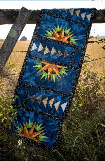Quilt with geometric patterns hanging on a wooden fence in a field Farmhouse Window Quilt Pattern Table Runner- Designed by Judy Niemeyer - Carmon's Quilt Shop