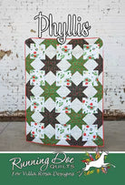 Quilt with star patterns displayed against a white brick wall, featuring Villa Rosa Designs branding. Quilt pattern Carmon's Quilt Shop