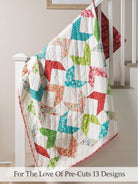 Carmon's Quilt Shop For the Love of Precuts pattern book featuring a colorful geometric quilt draped on a railing