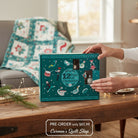 Carmon's Quilt Shop 12 Days of Christmas advent box with turquoise festive illustrations on a rustic wooden table.