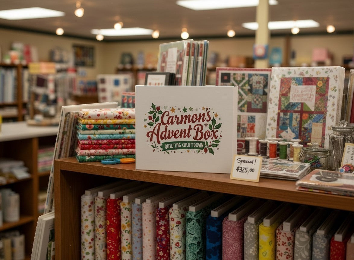 Carmon's Quilt Shop limited-edition advent box displayed on a wooden shelf with stacks of colorful quilting fabrics.
