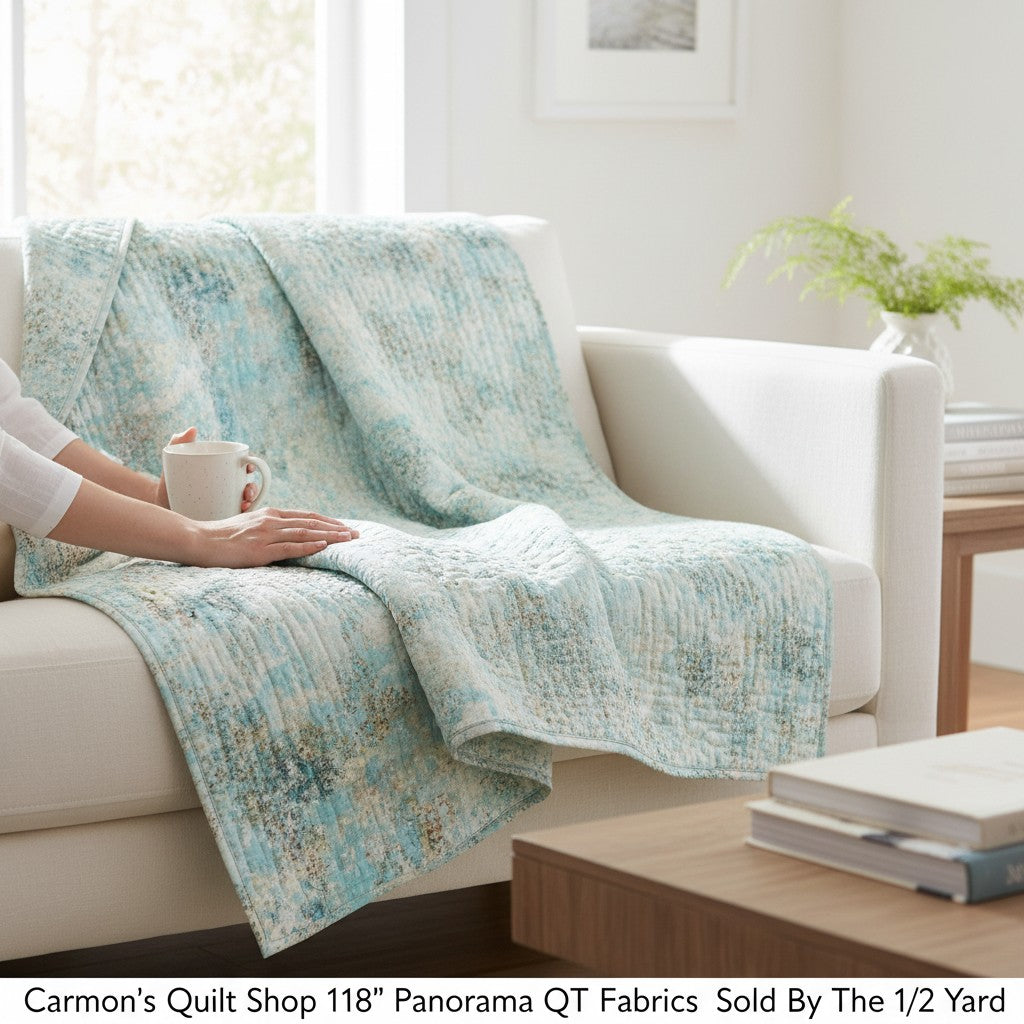 Carmon's Quilt Shop light aqua mottled texture 118 inch wide cotton quilting fabric draped over a white sofa