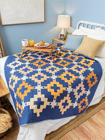 Carmon's Quilt Shop features a blue and orange patchwork quilt from Autumn Quilting with Wendy Sheppard on a bed.