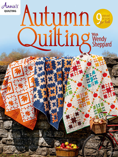Carmon's Quilt Shop Autumn Quilting book cover featuring three colorful seasonal patchwork quilts on a stone wall.