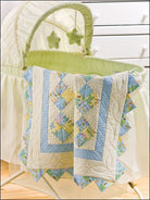 Carmon's Quilt Shop baby quilt featuring pastel blue and yellow patchwork patterns draped over a bassinet