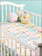 Carmon's Quilt Shop baby quilt pattern book featuring pastel patchwork designs on a white crib with matching pillows