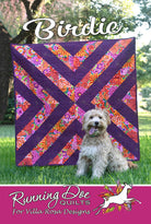 Carmon's Quilt Shop Birdie quilt pattern featuring a purple and floral geometric diagonal design with a small dog