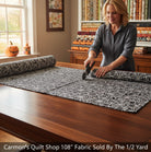 Carmon's Quilt Shop QT Fabrics black cotton quilting fabric with white spiderweb print being cut on a wooden table.